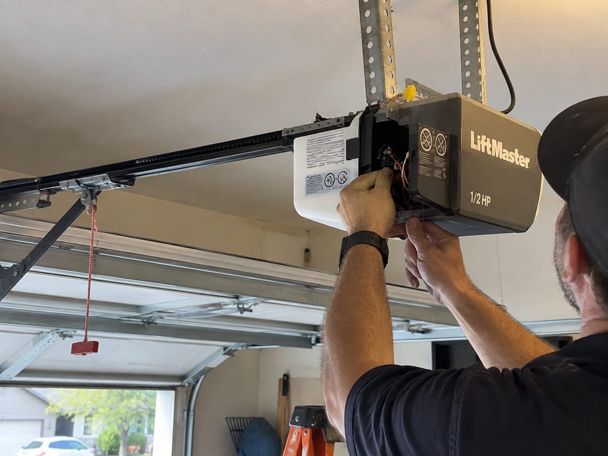 Technician working on a ceiling-mounted garage door opener